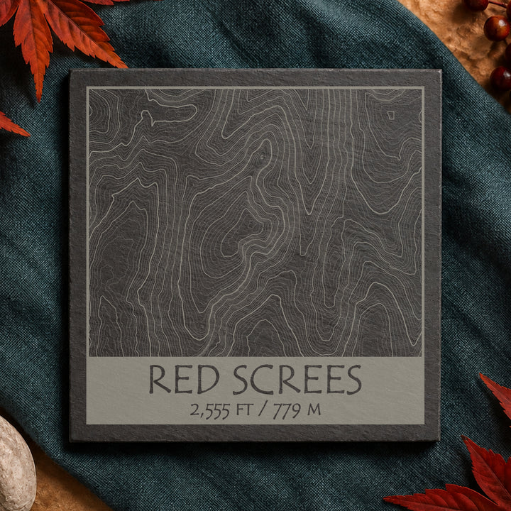 Red Screes topographic slate coaster on pale stone with autumn leaves and map details