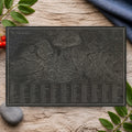 The Wainwrights natural slate placemat on a pale oak table with blue linen and rowan leaves: a contour map of the Lake District with all 214 fells numbered and listed in a key