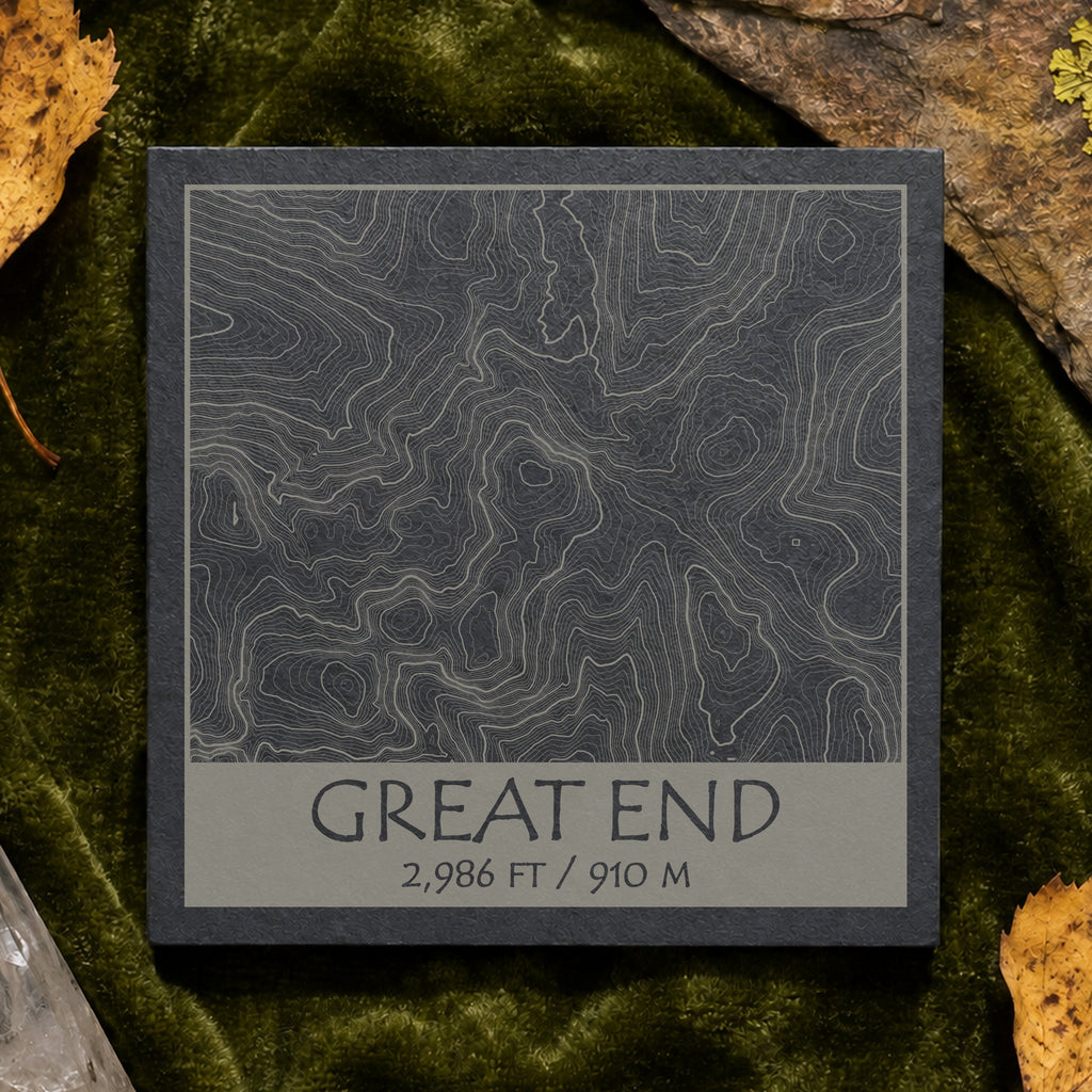 Great End topographic slate coaster on pale stone with quartz, moss and green leaves–