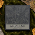 Great End topographic slate coaster on pale stone with quartz, moss and green leaves–