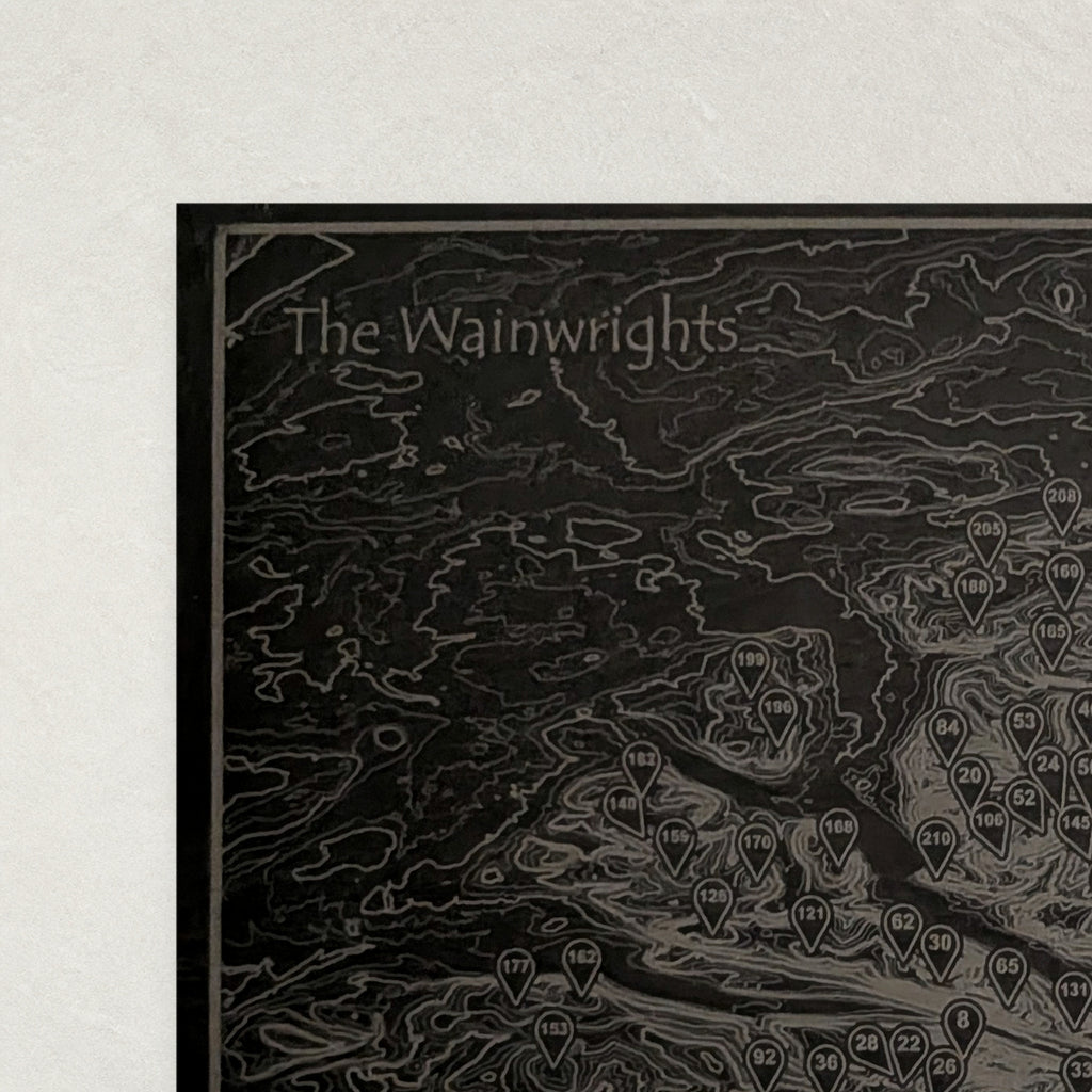 Close view of the top corner of The Wainwrights slate placemat showing the engraved title, border line and contour lines